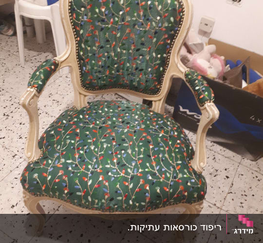 כיסא מרופד בבד ירוק עם דוגמת פרחים צבעונית